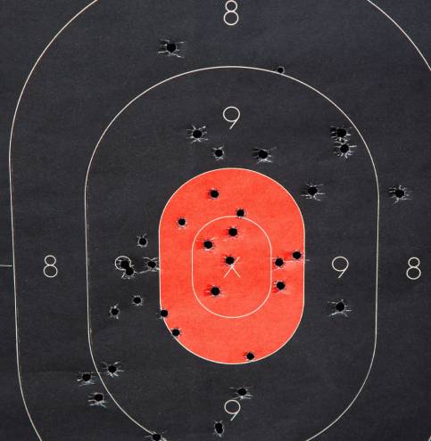 Close up of red and black shooting target with bullet holes.